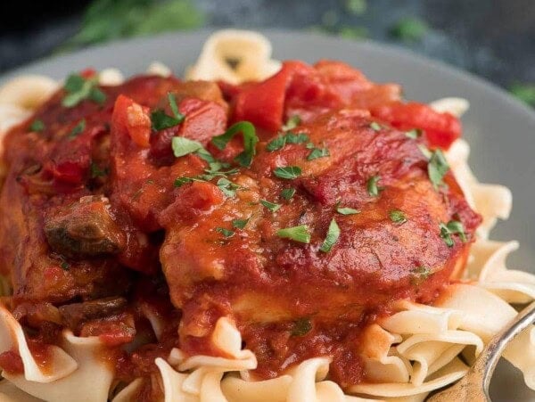 Chicken cacciatore on grey plate served over pasta