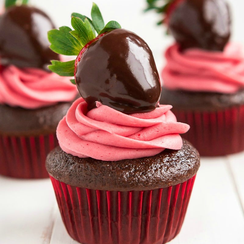 Valentine's Day Desserts - Chocolate cupcakes topped with pink frosting and a ganache smothered strawberry. 