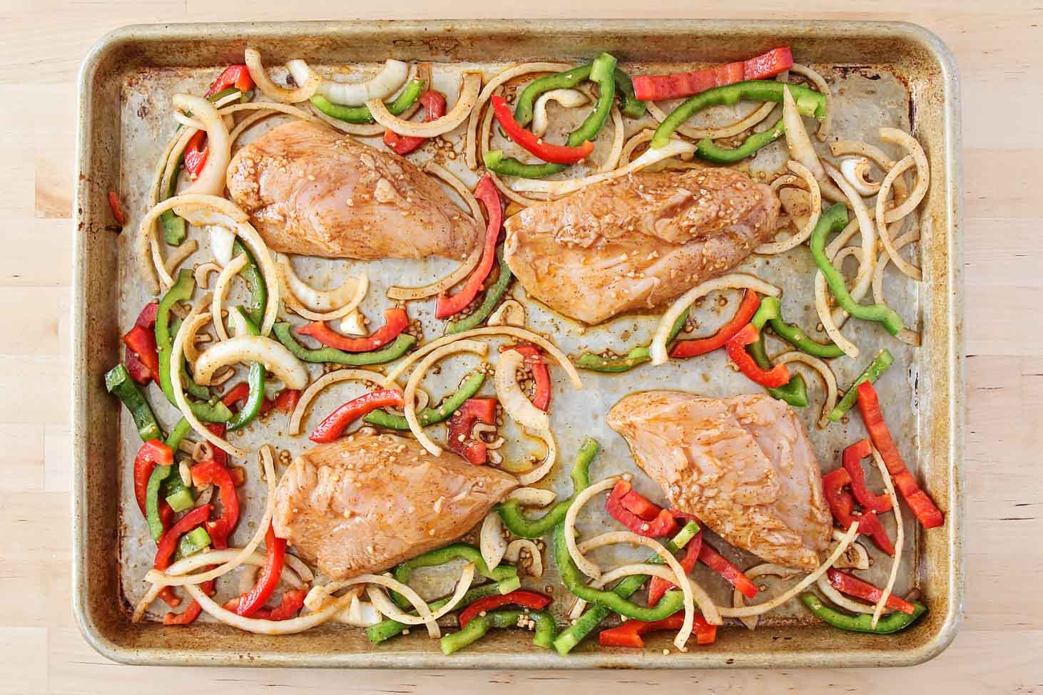 Marinated chicken and vegetable slices on a sheet pan