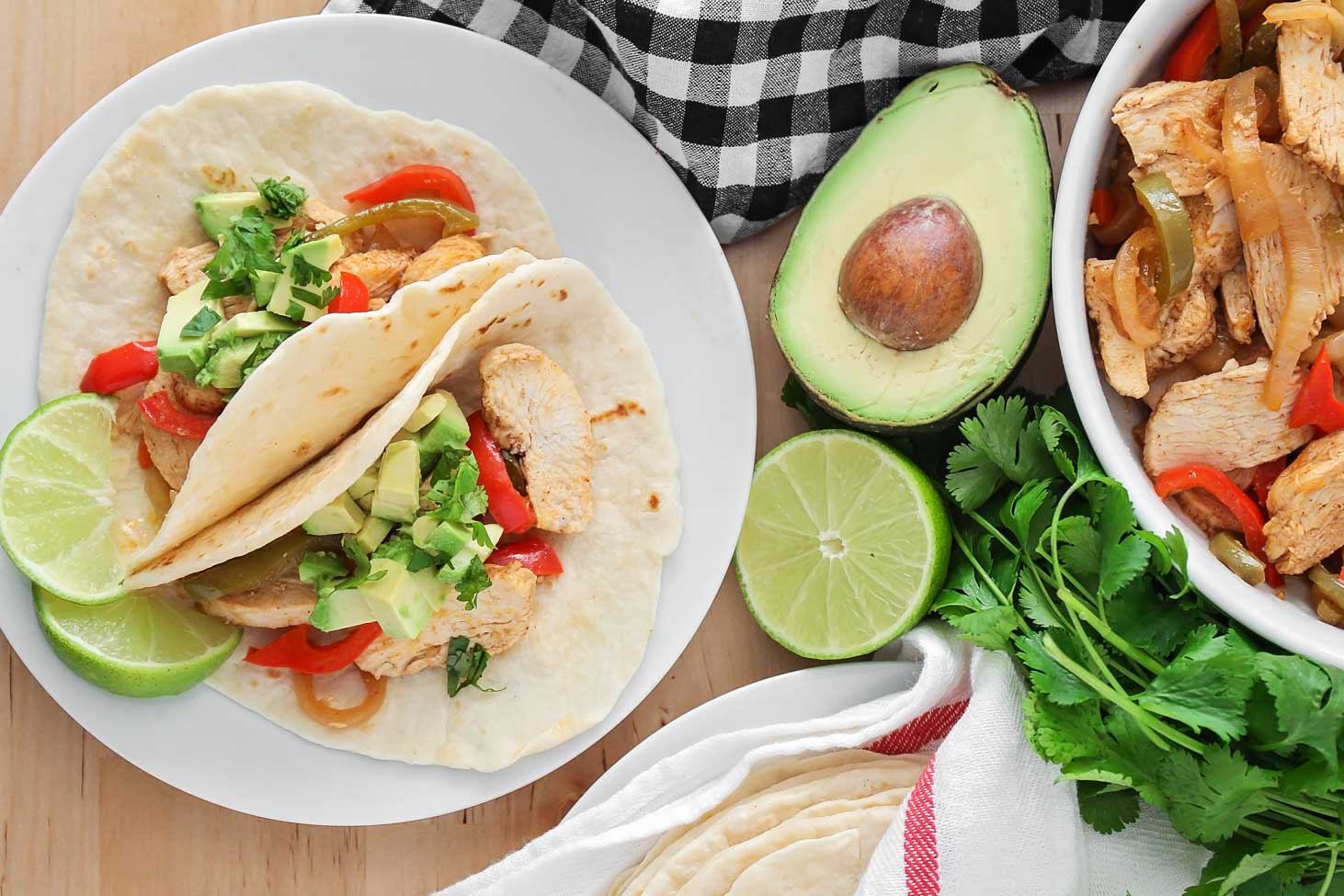 Two sheet pan chicken fajitas on a white plate.