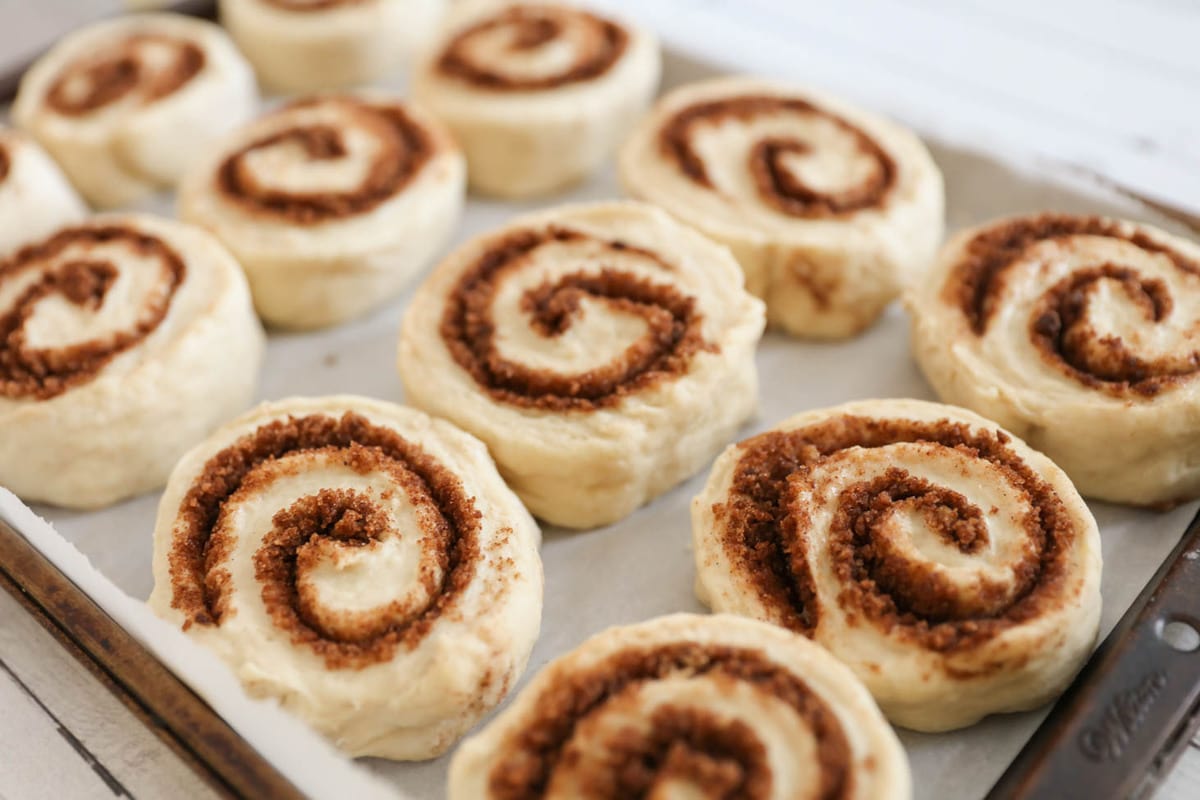 Easy Cinnamon Rolls Recipe sliced and proofing on a sheet pan.