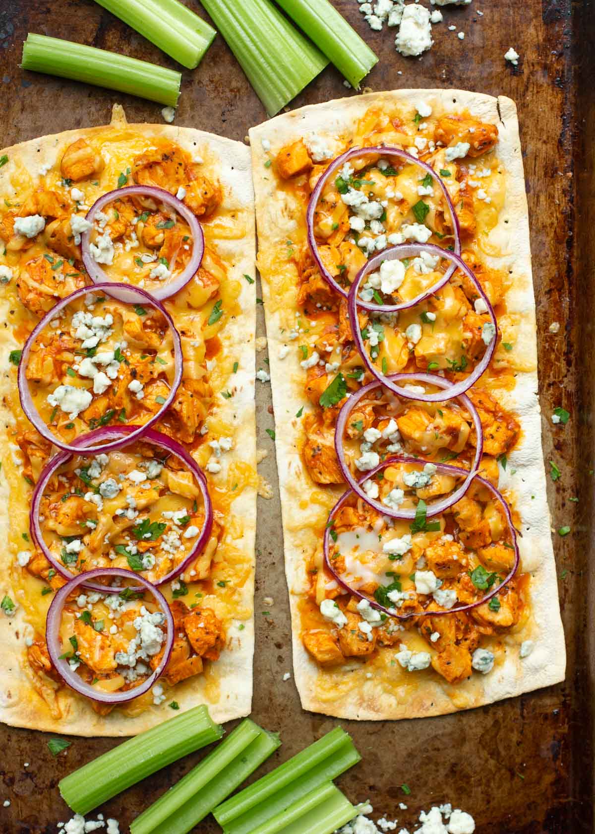 Two healthy flatbread pizzas with buffalo chicken and onions