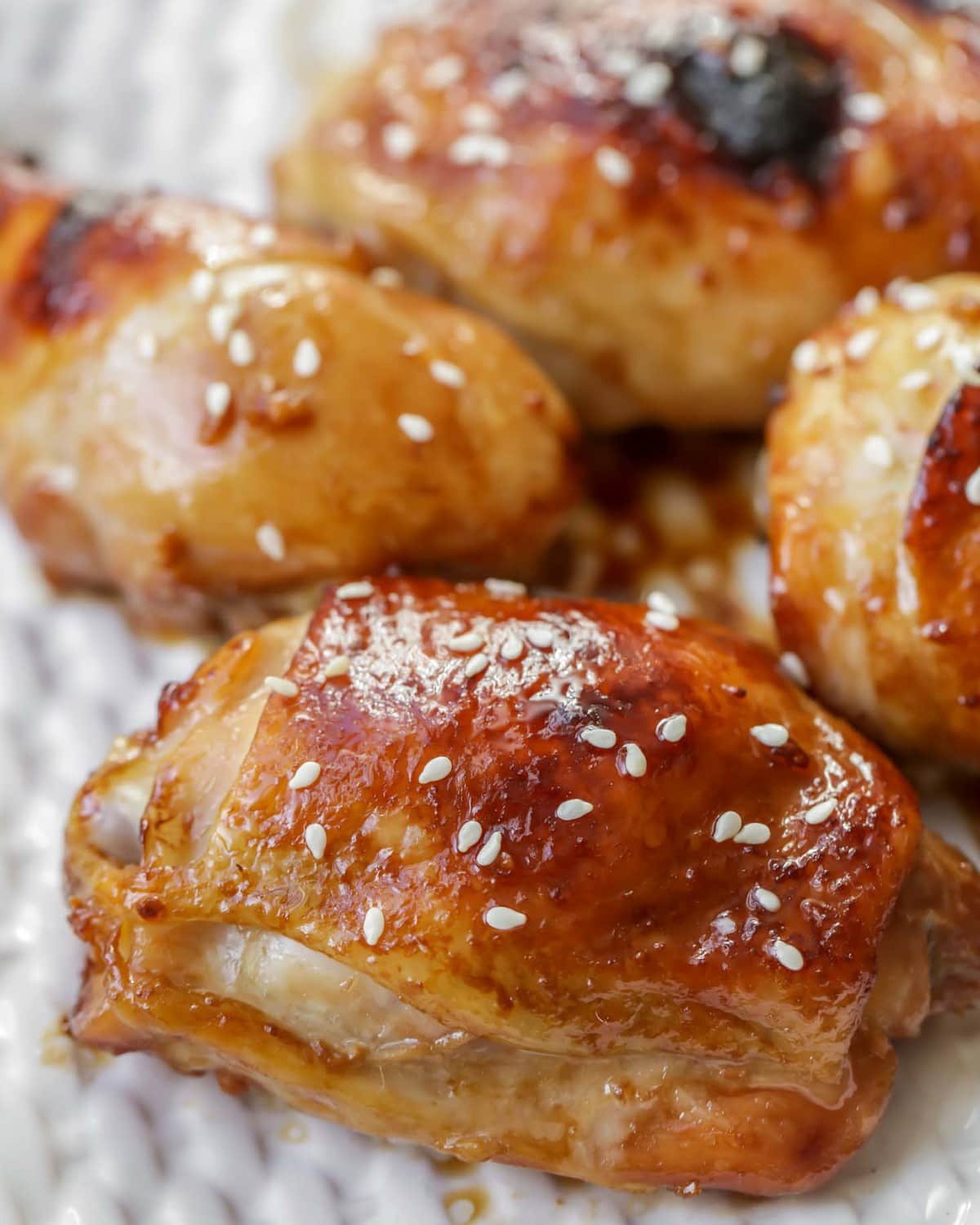 baked Chinese Honey Garlic Chicken thighs topped with sesame seeds on a baking sheet