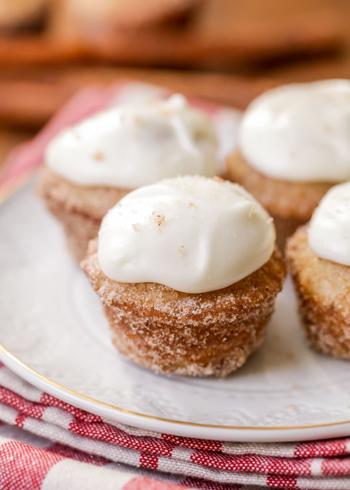 Mini donut muffins coated in cinnamon sugar and topped with cream cheese frosting