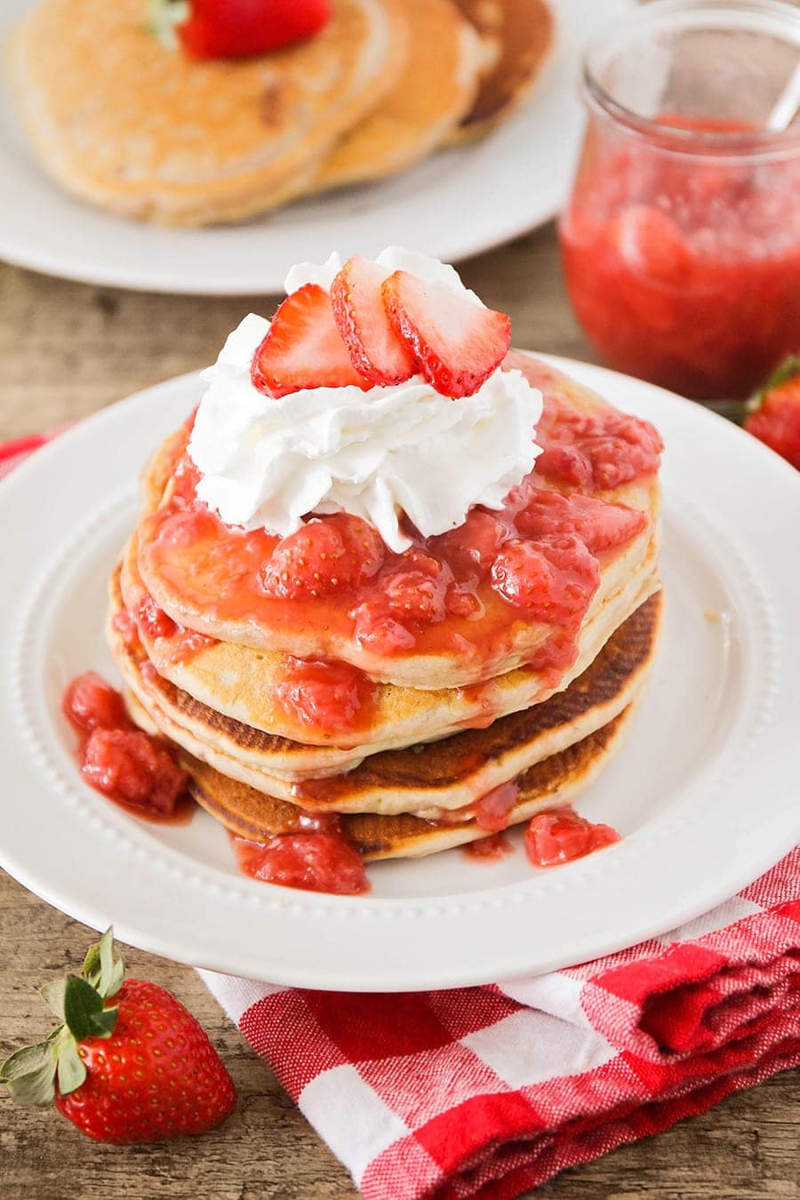 Easy pancake recipe - Stack of strawberry pancakes with whipped cream and strawberry on top.