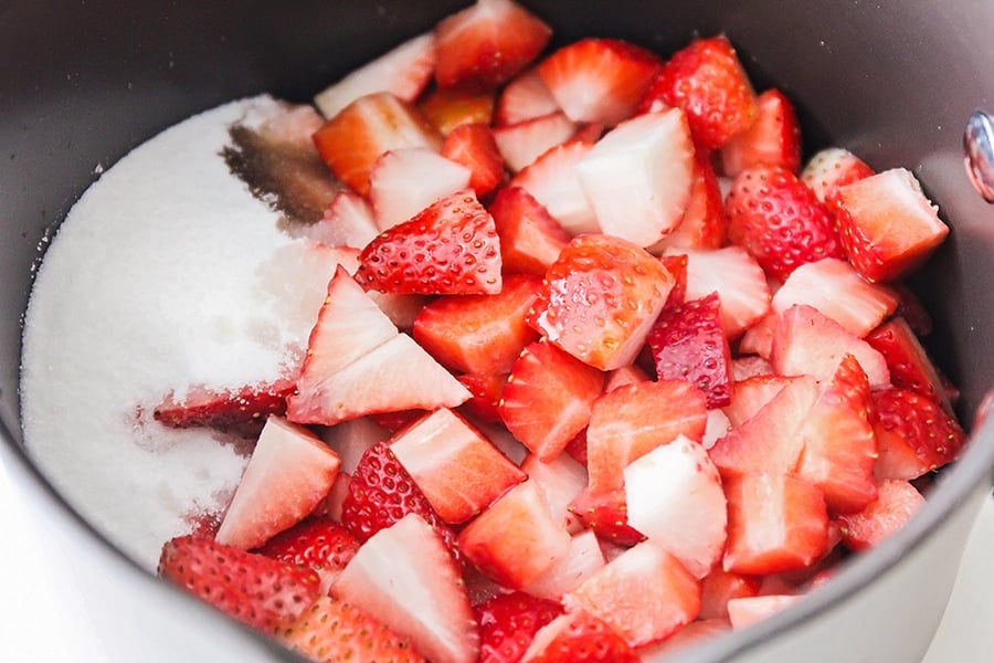 Strawberry chunks and sugar in pan