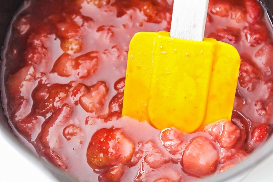 Strawberry pancake syrup cooking in pan with yellow spatula