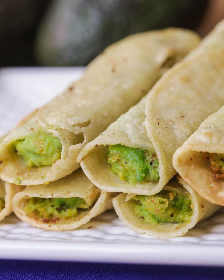 Avocado Taquitos fried and stacked on a white plate