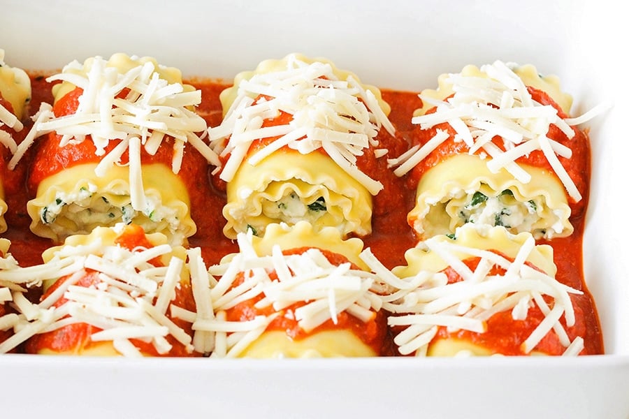 Spinach Lasagna rolls topped with marina sauce and shredded cheese.