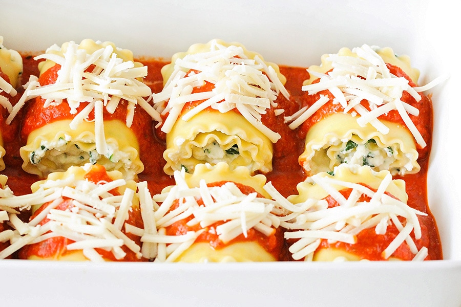 Spinach Lasagna rolls topped with marina sauce and shredded cheese.