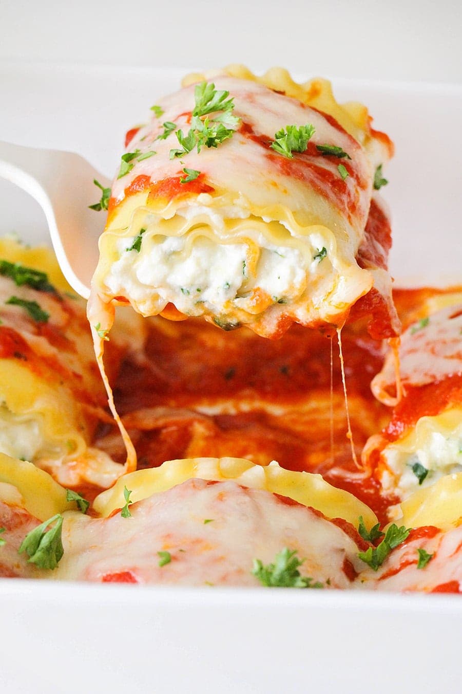 Spinach Lasagna Rolls being scooped with a serving spatula.
