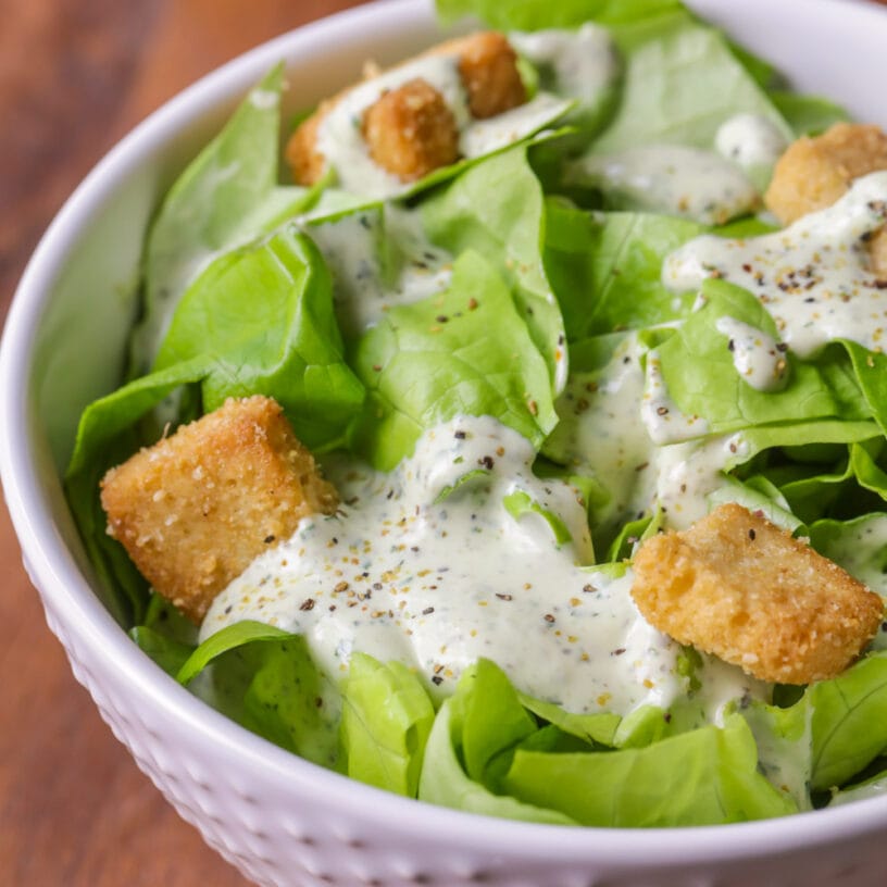 Valentines Dinner Ideas - green salad topped with croutons and a creamy pesto dressing in a white bowl. 