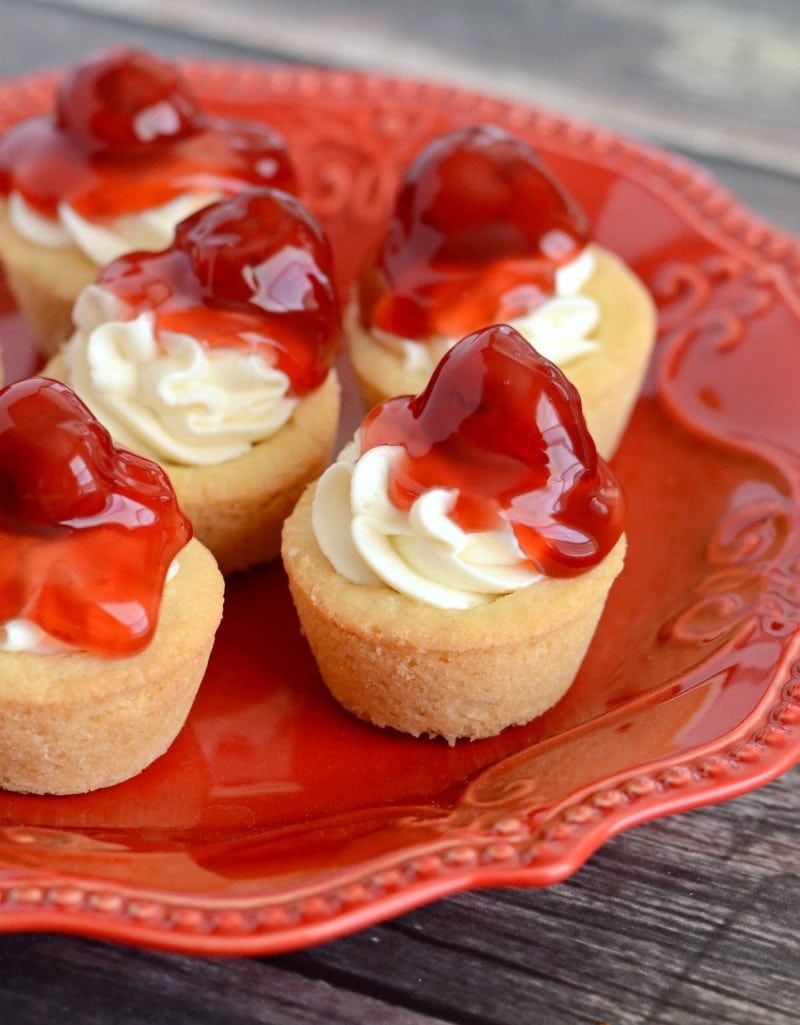 Mini Cherry Cheesecake Cookie Cups - All the flavor of cherry cheesecake, served in mini sugar cookie cups! They're super easy to make and are perfect for serving a crowd!!