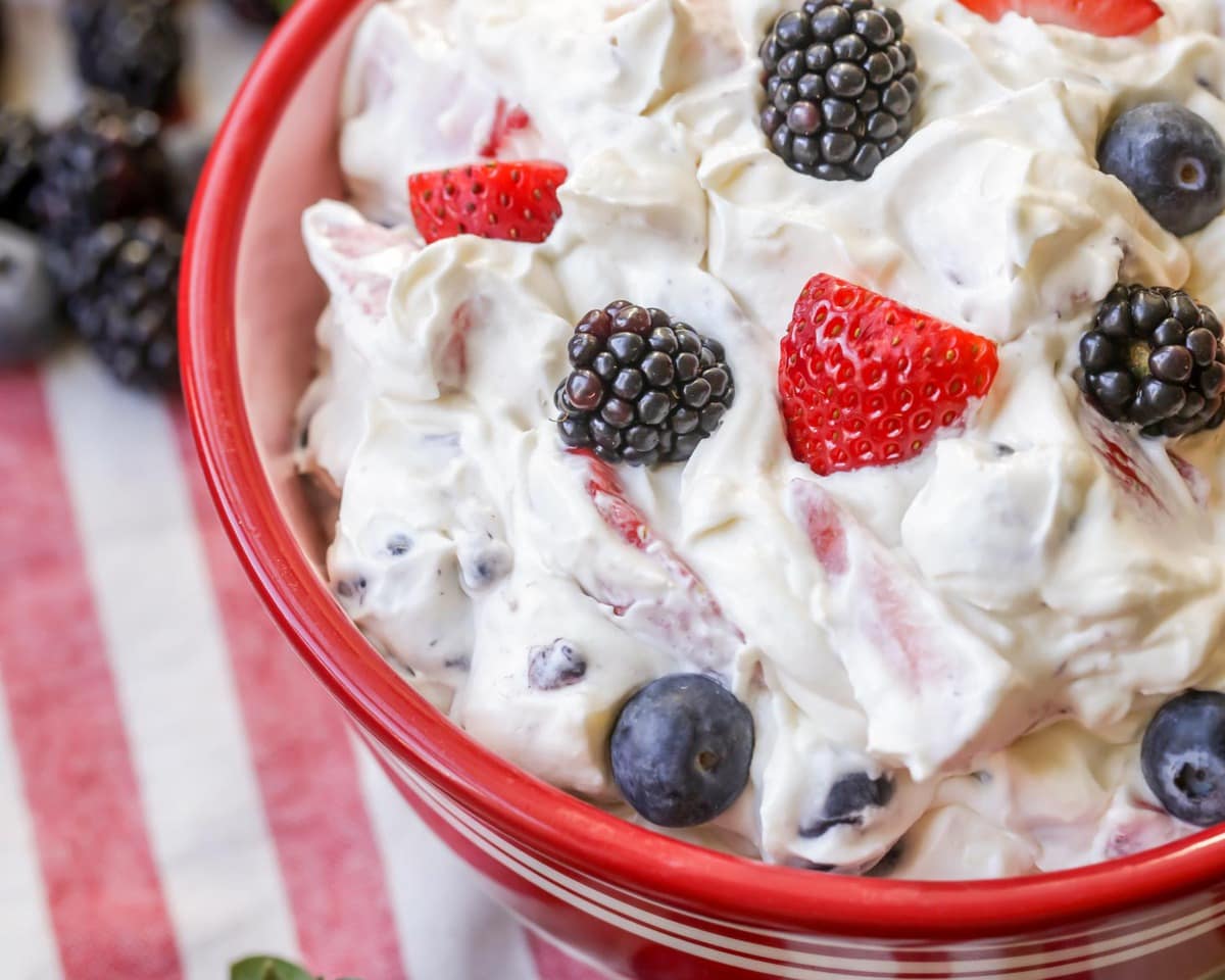 Cheesecake salad in a red bowl, made from seasonal summer berries.