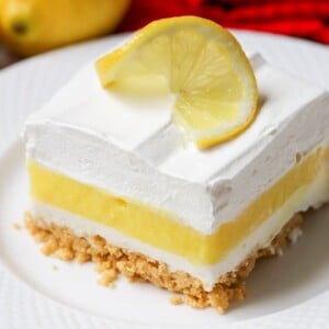 A slice of layered lemon lasagna topped with a fresh lemon slice.
