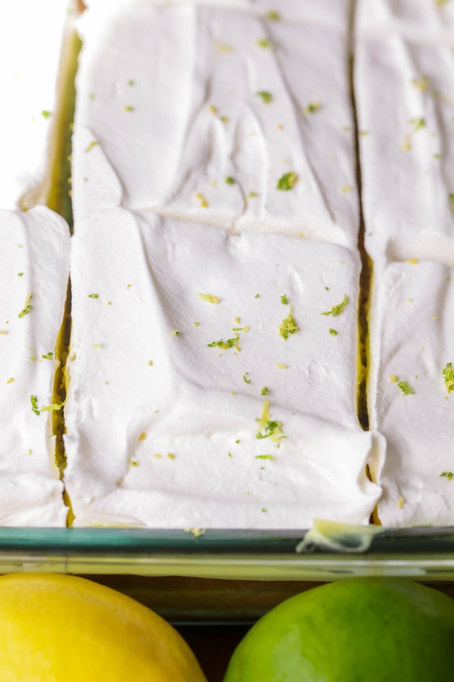 Sliced whipped cream covered lemon lime poke cake