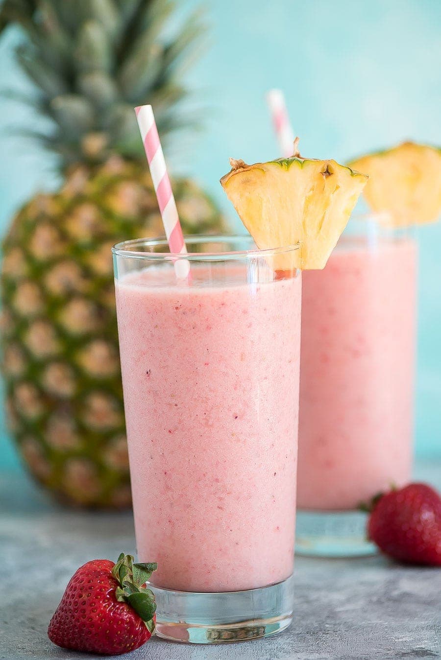 Peach smoothie - aloha tropical smoothie garnished with a slice of pineapple and a pink and white striped straw.