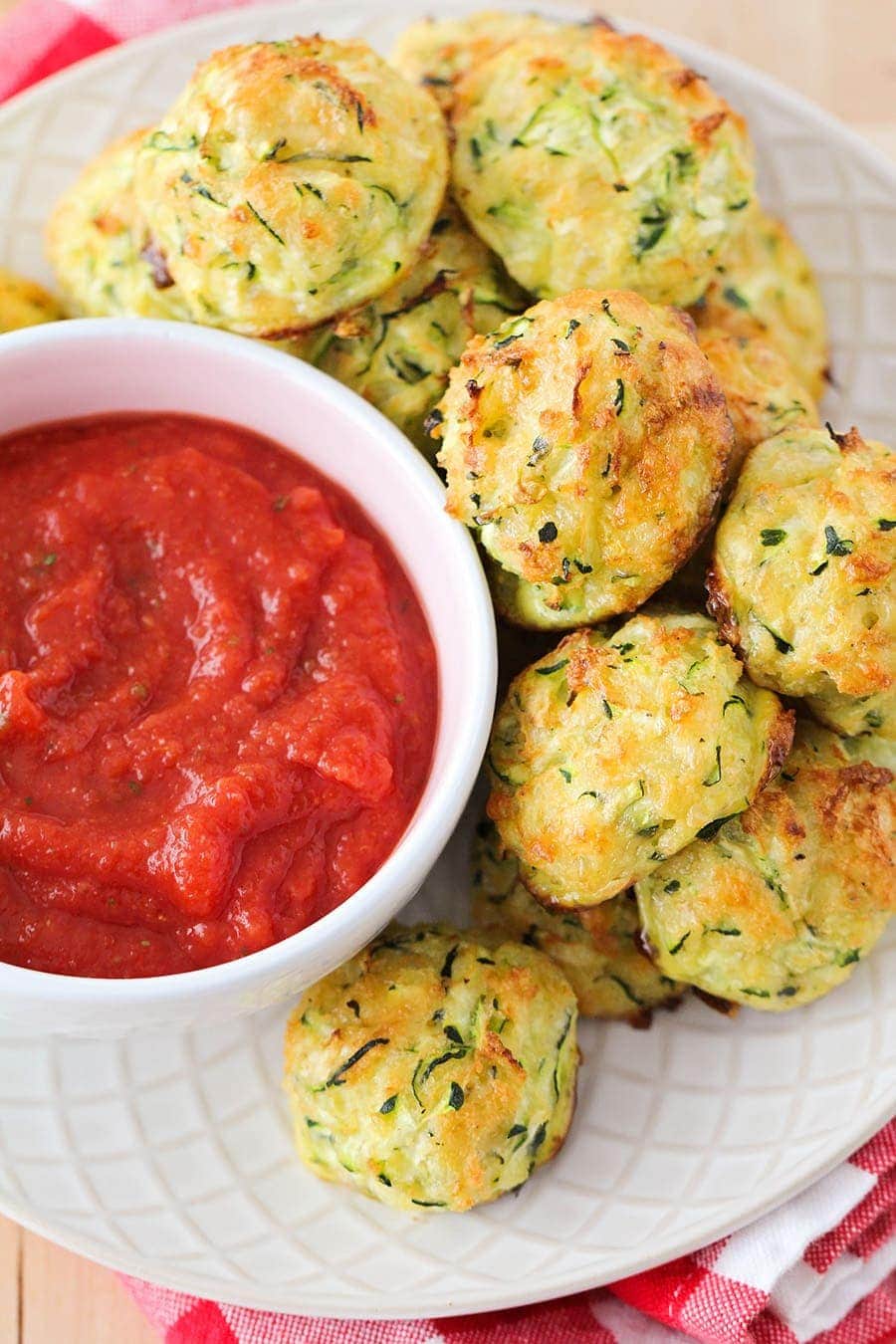 Cheesy Zucchini Tots on a white plate with marinara