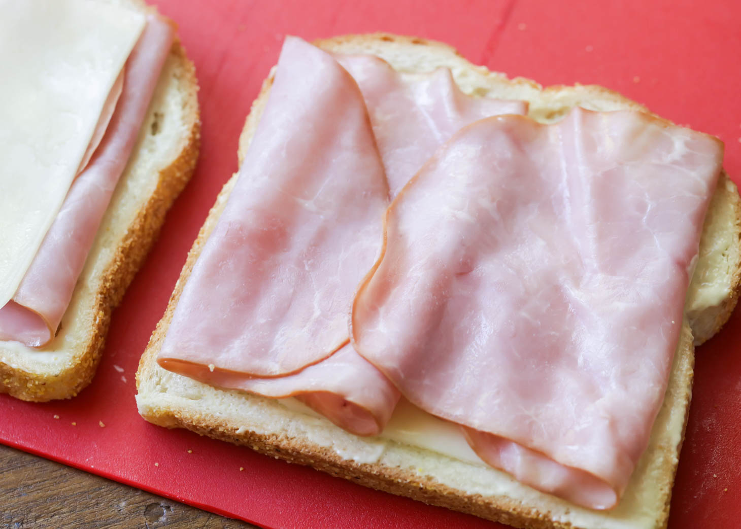 Layering ham and cheese on slices of bread to make Croque Monsieur recipe.