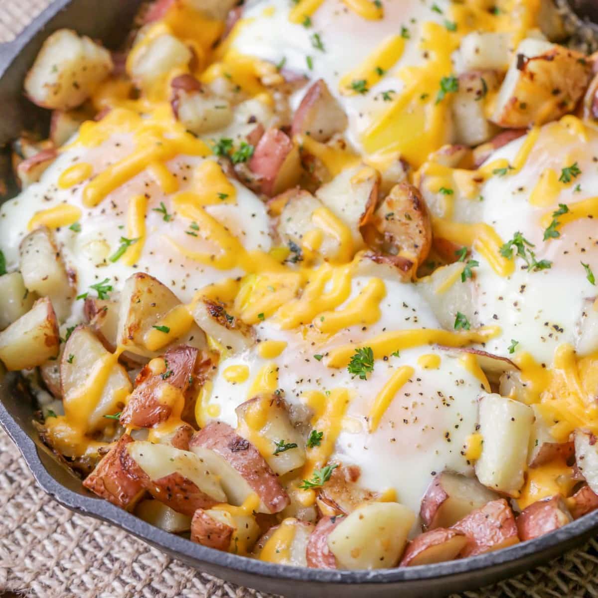 Breakfast Egg Recipes - eggs and potatoes topped with melted cheddar cheese in a cast iron skillet. 