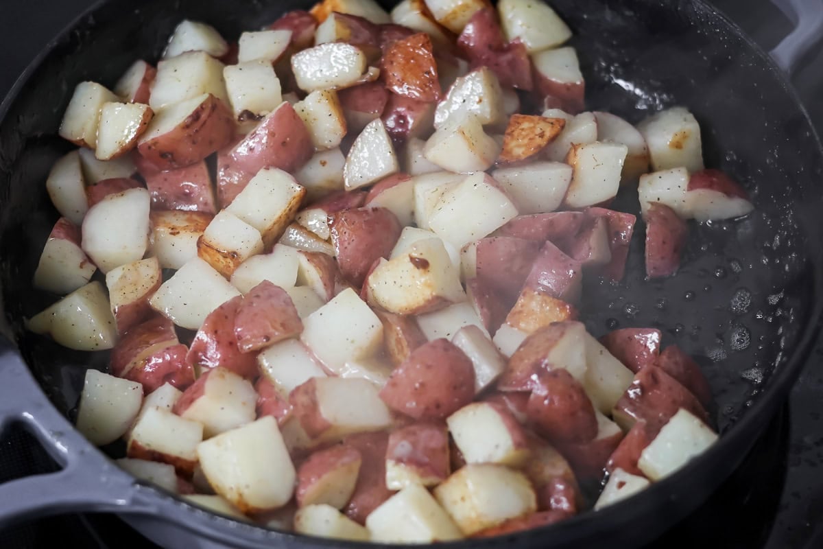 Cut potatoes cooking in a skillet for eggs and potatoes.