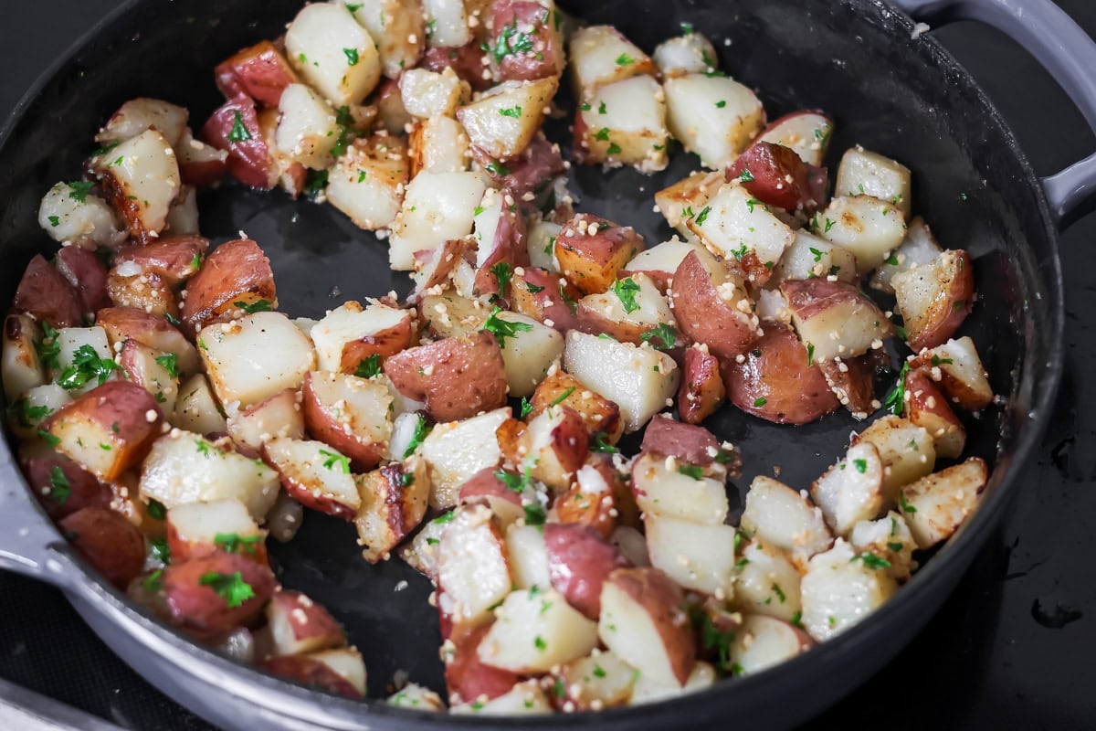 Seasoned potatoes cooking in a skillet for eggs and potatoes.