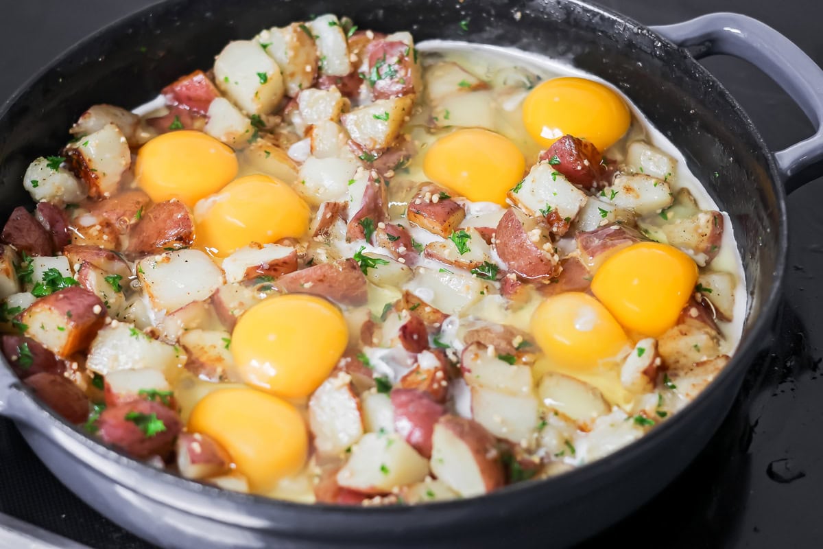 Adding ingredients to a skillet for eggs and potatoes.