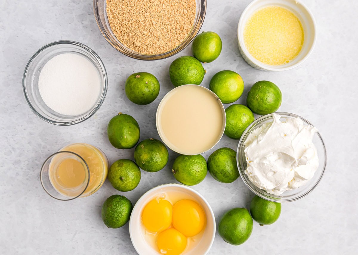 Key lime pie bars are a favorite dessert in a bar - a buttery graham cracker crust and a tart and creamy lime filling!! Ingredients for key lime bars on a kitchen counter.