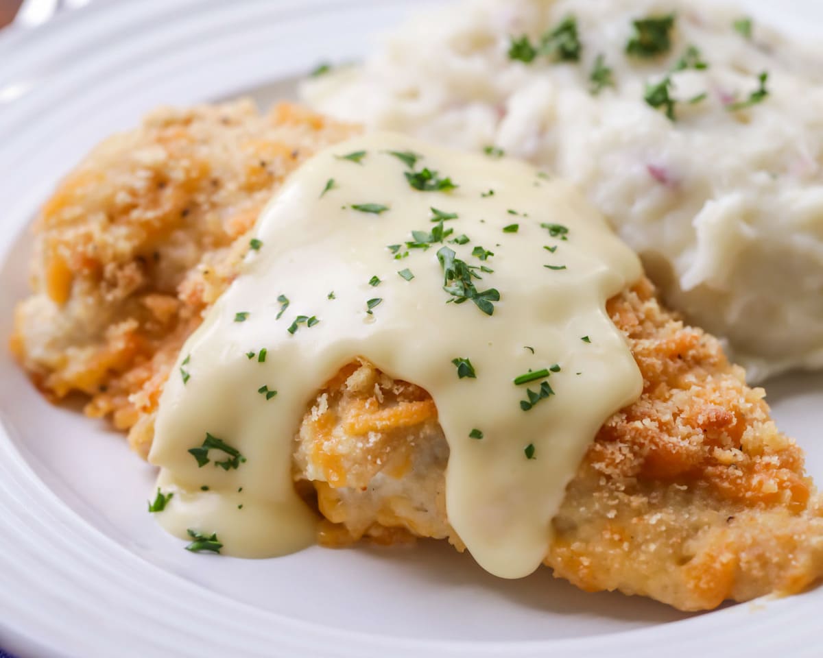 Ritz cracker chicken with sauce served on white plate.