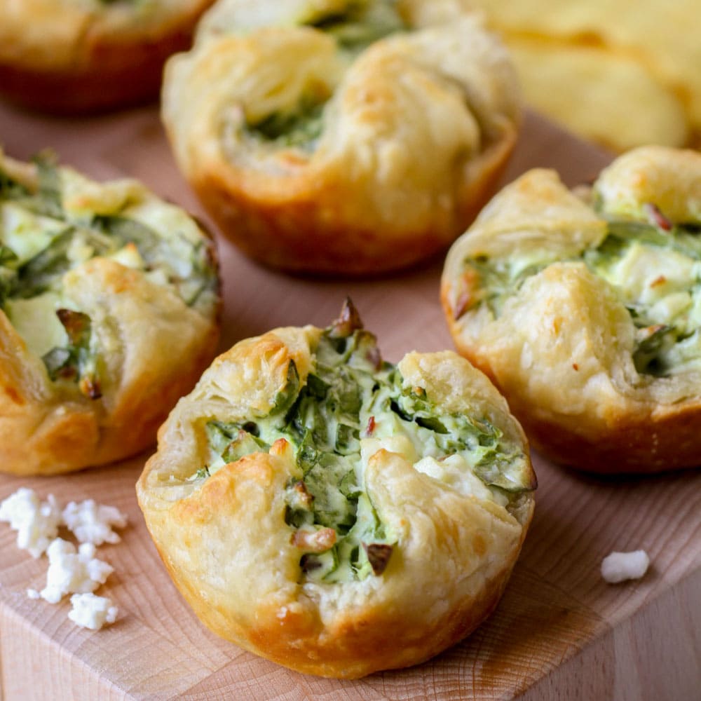 Christmas appetizers -  several spinach puffs on a wooden board.