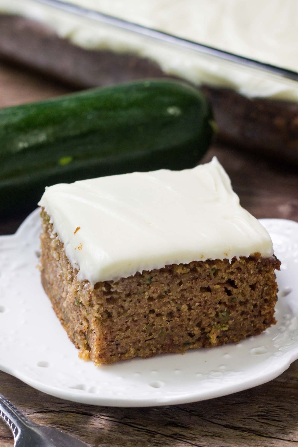 Zucchini cake with cream cheese frosting on a white plate