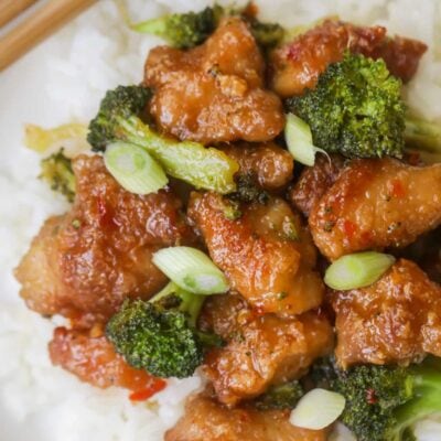 general tso chicken served over white rice and plate with chopsticks