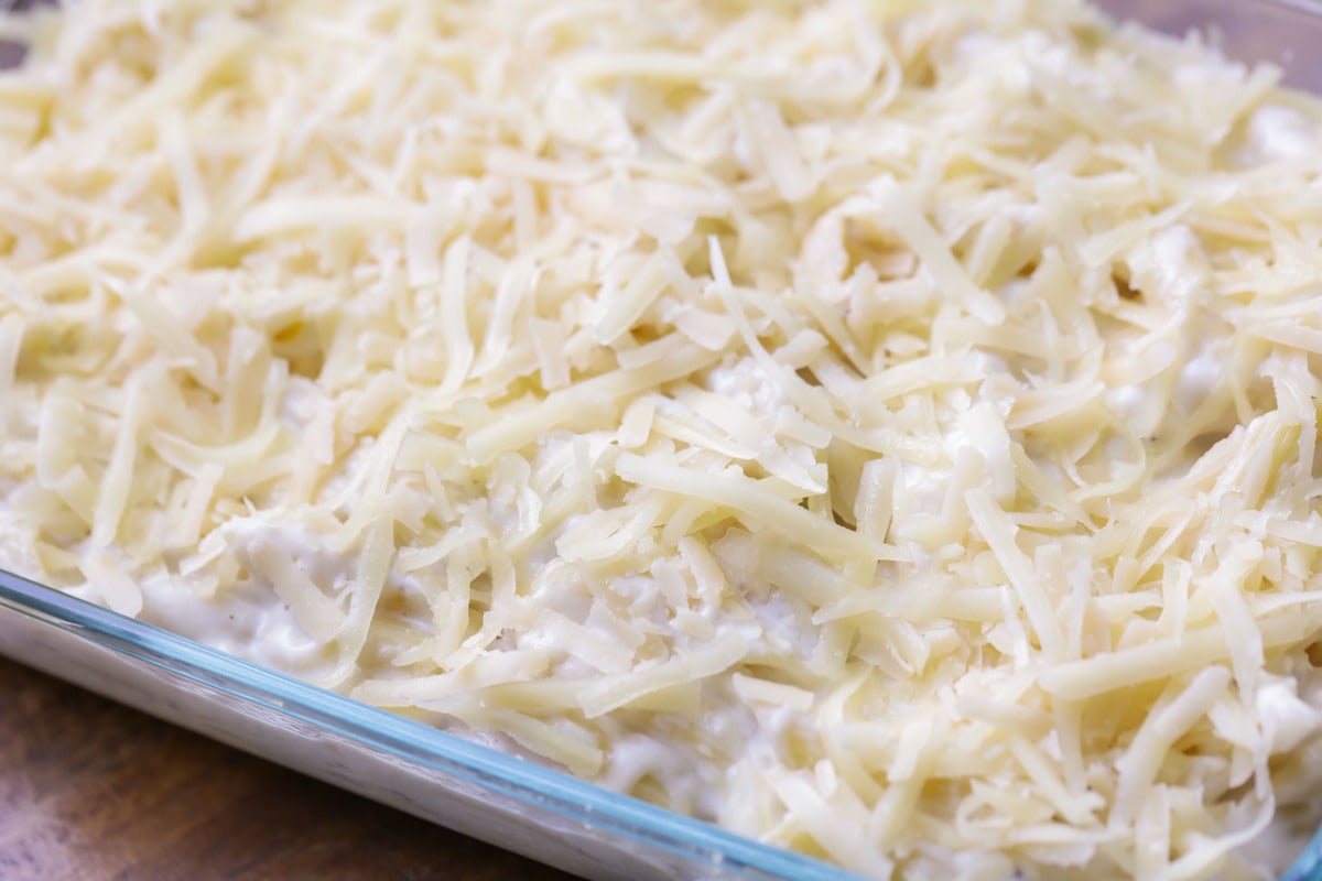 A glass dish of pasta topped with shredded cheese.