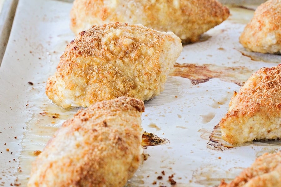 Baked Chicken on a baking sheet lined with parchment paper.