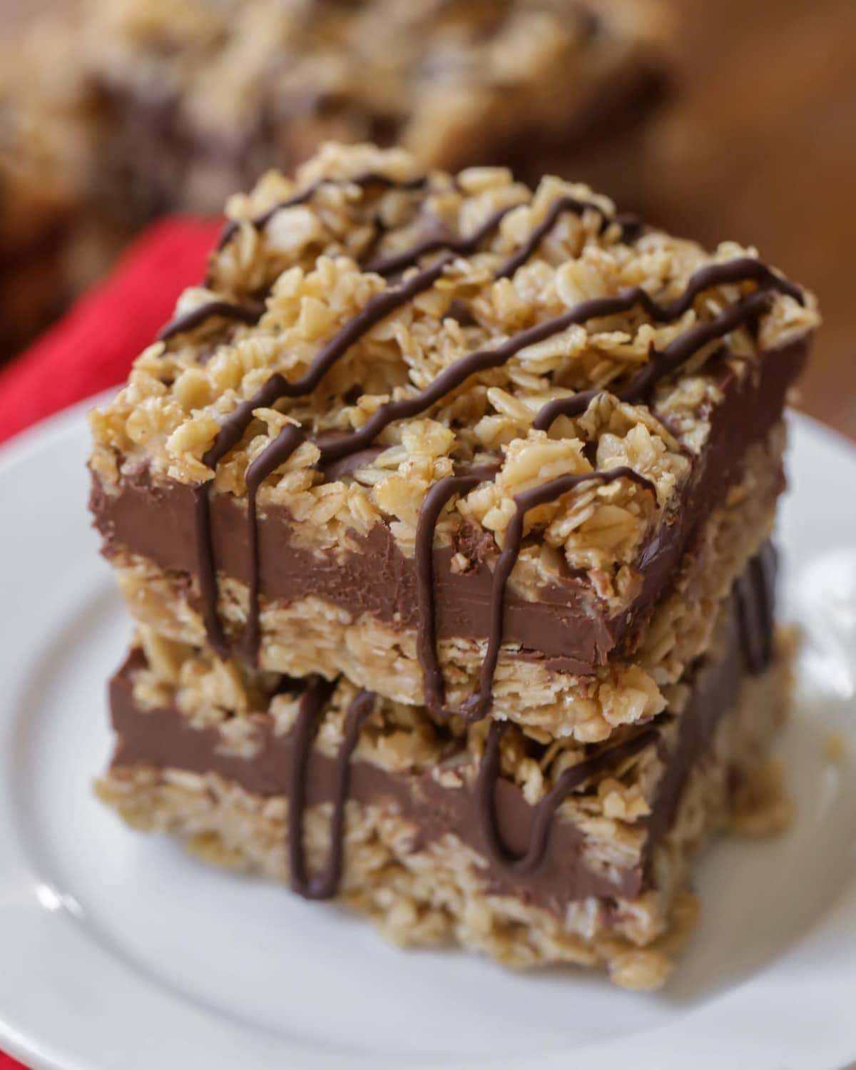 Cookie bar recipes - no bake chocolate oat bars drizzled with chocolate and stacked on a white plate.
