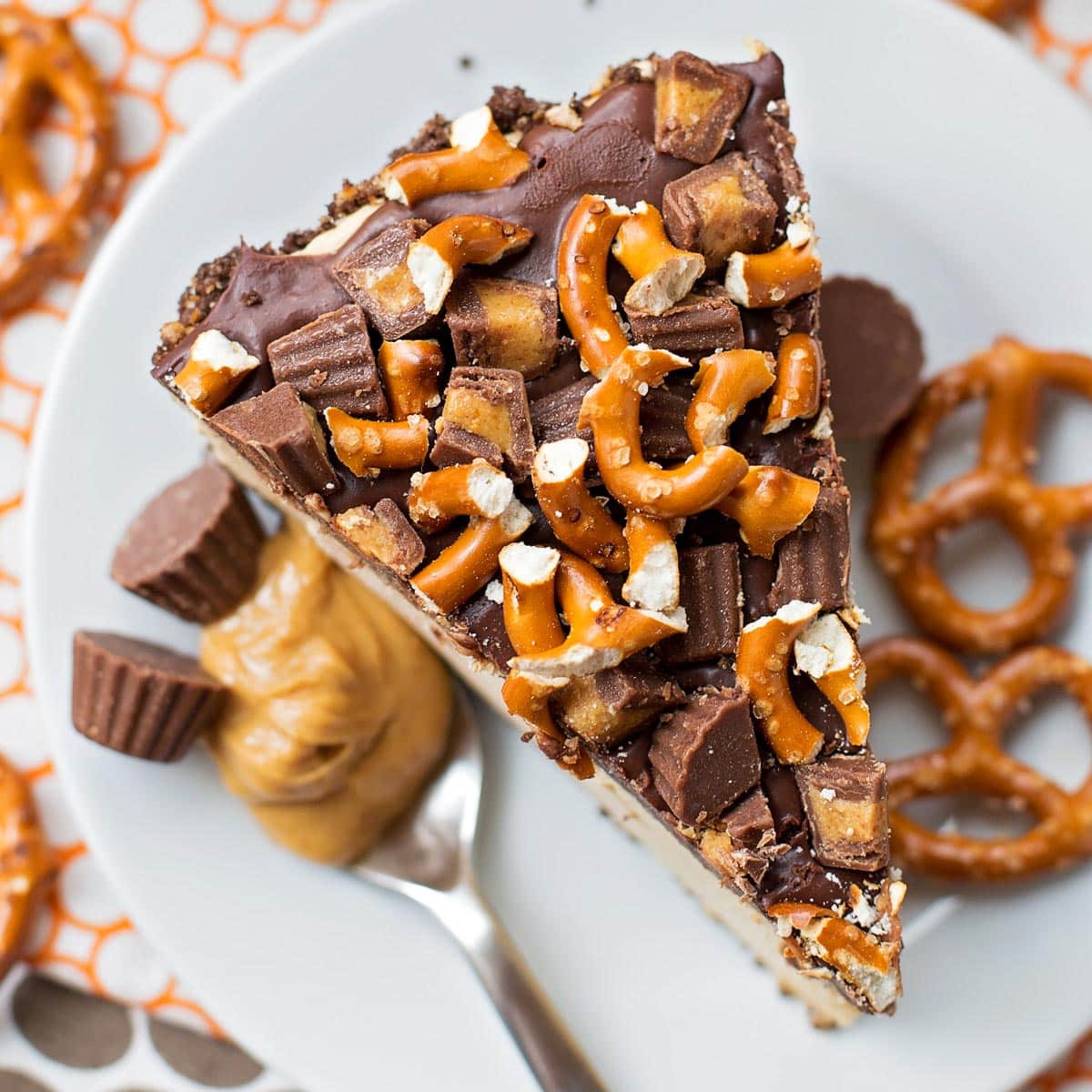 Peanut butter pie topped with pretzels and peanut butter cups on a white plate