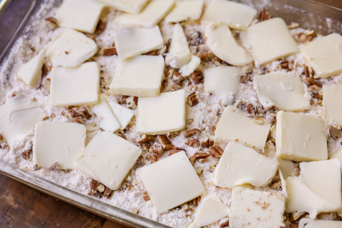 Nuts and crumb topping with butter on pumpkin cake batter.