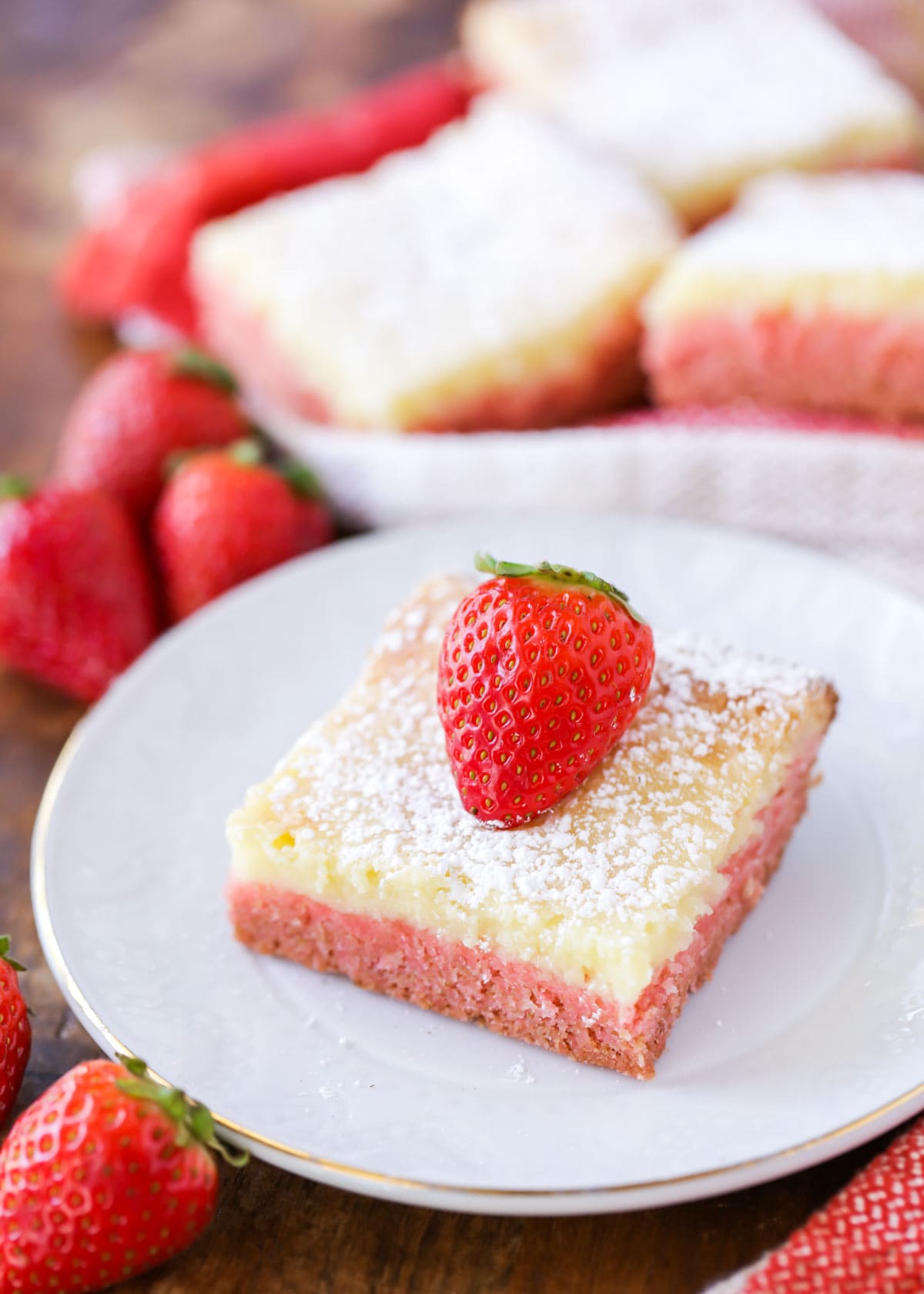 Strawberry Gooey Butter Cake slice served on a white plate with fresh strawberries.
