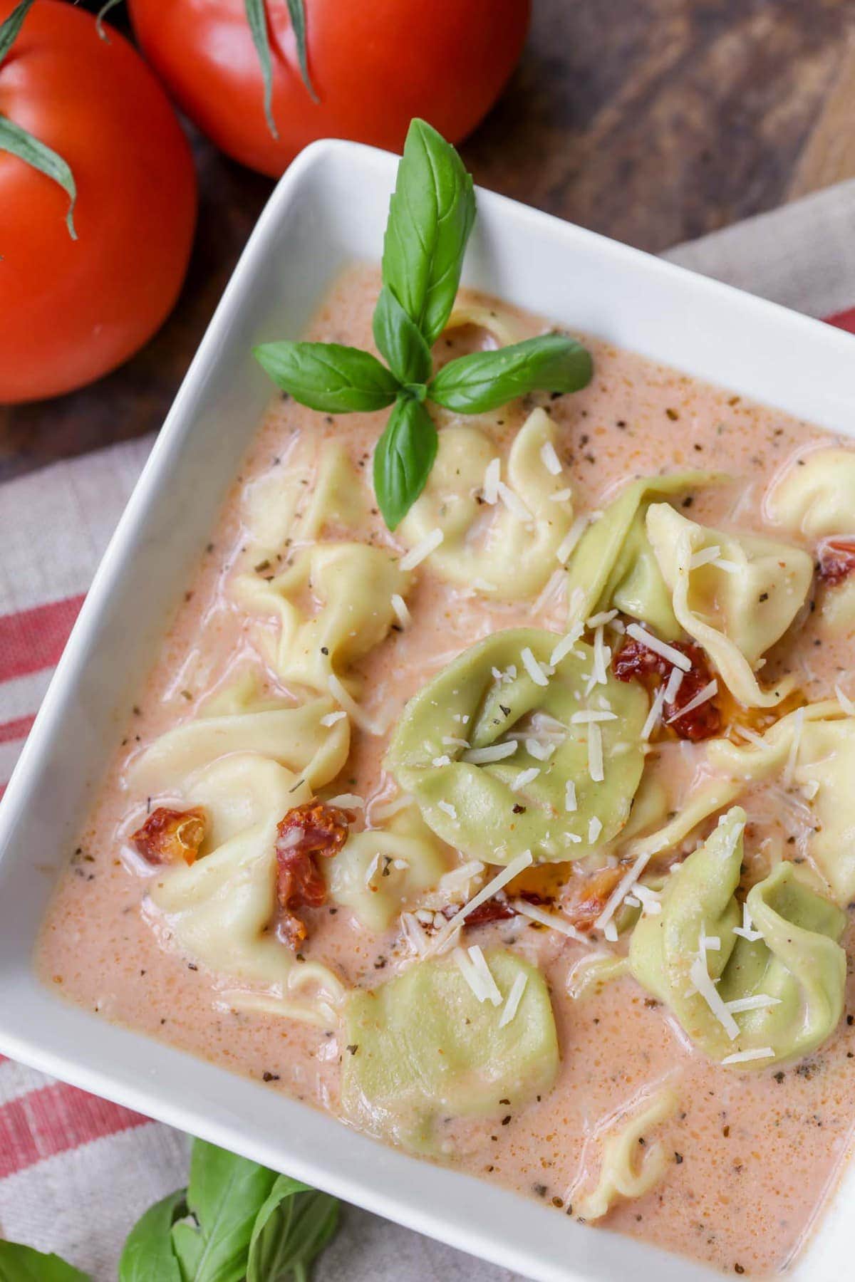 Bowl of creamy Tomato Tortellini Soup garnished with fresh basil.