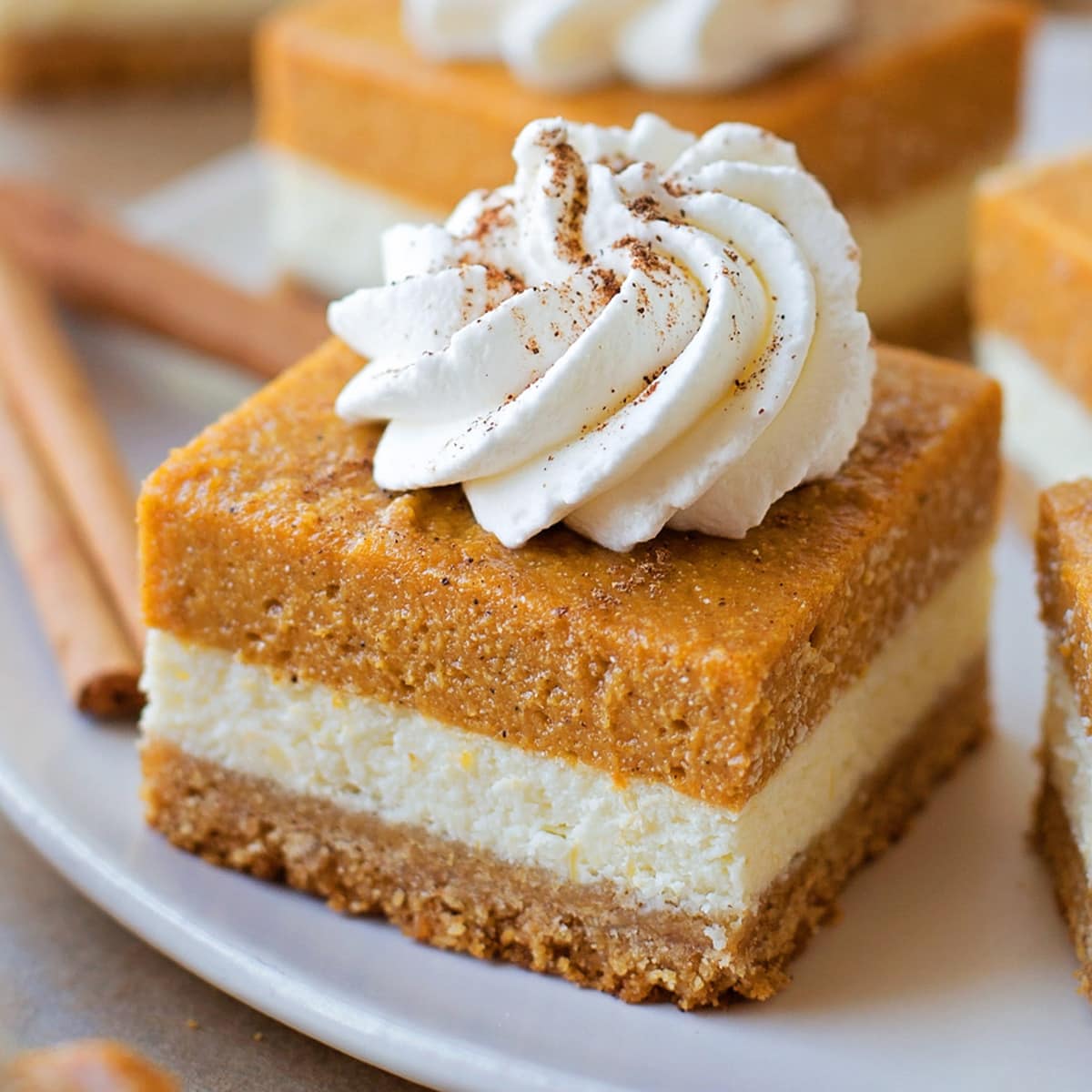 Pumpkin Pie Cheesecake Bars topped with a dollop of whipped cream.