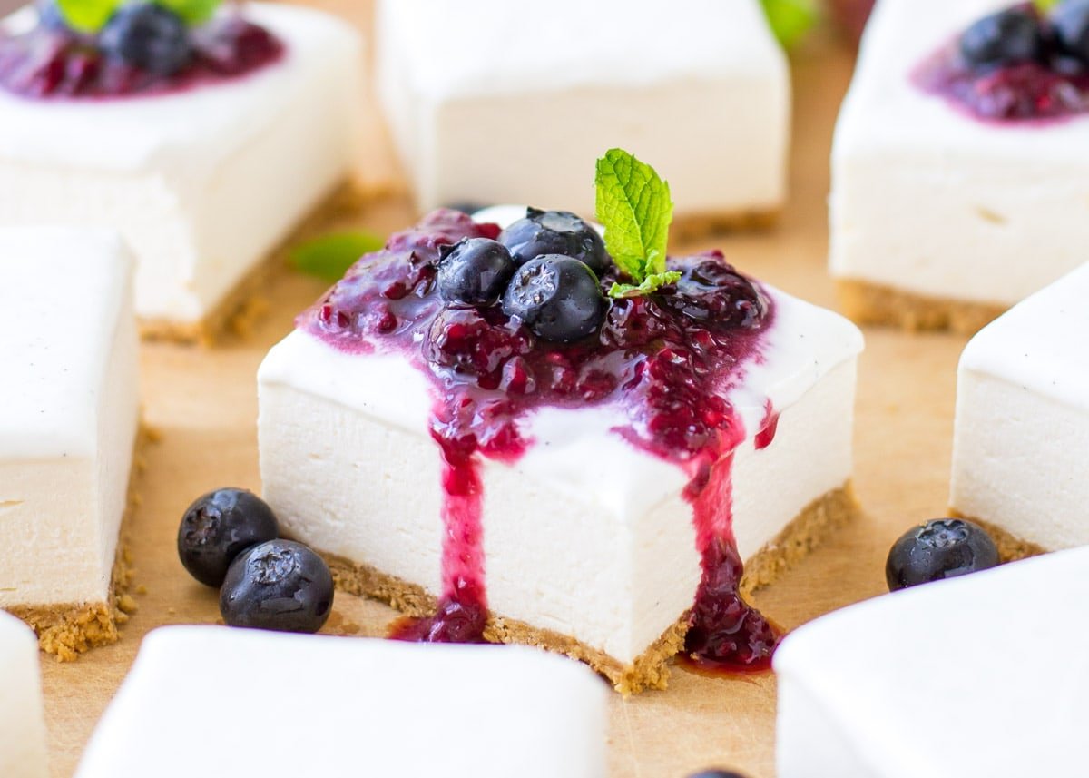 Close up of a no bake cheesecake bar topped with a berry sauce.