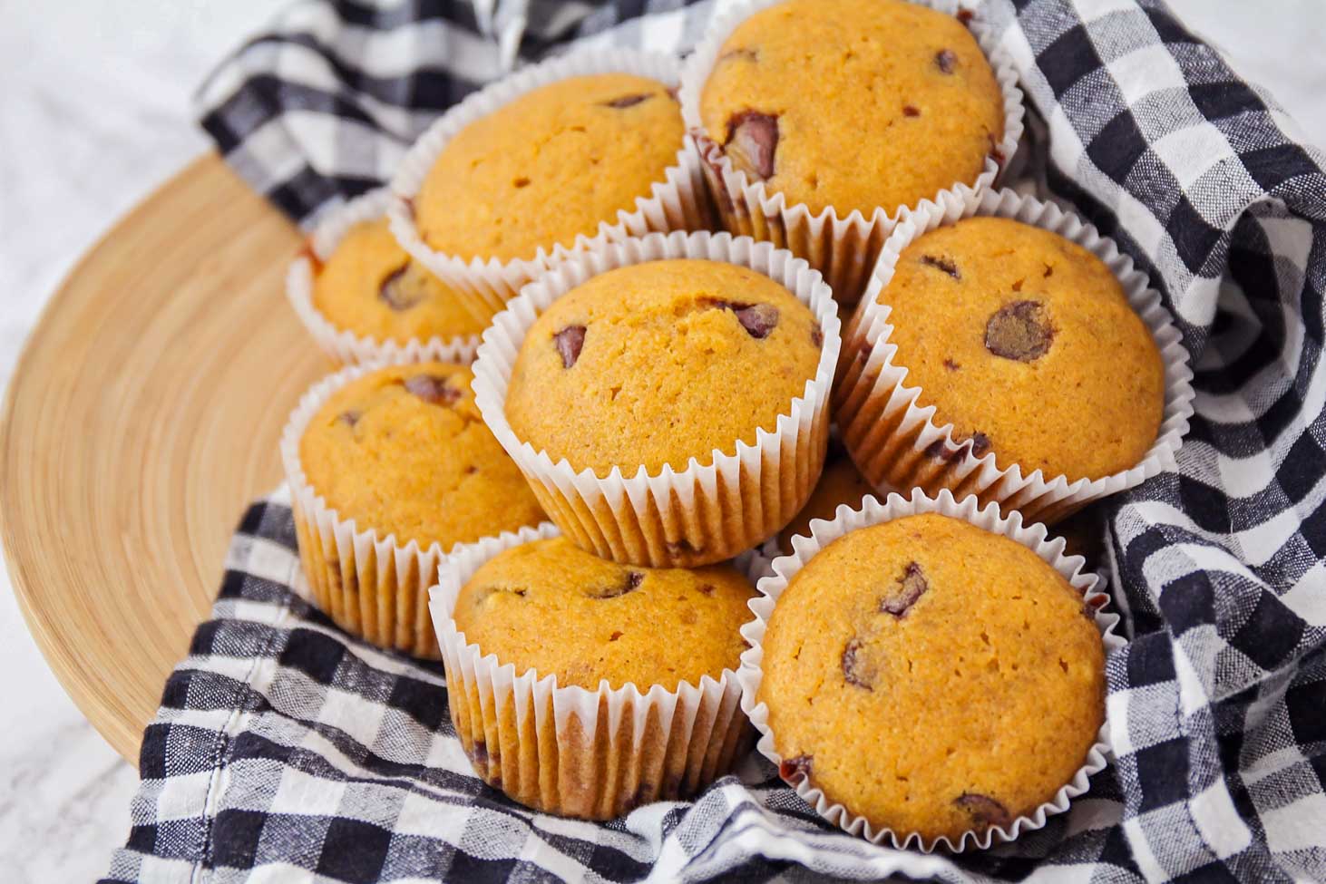 Pumpkin chocolate chip muffins stacked on a dish towel