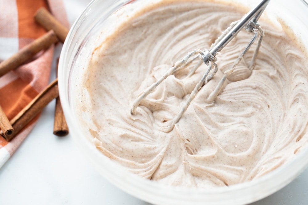 Cinnamon cream cheese frosting in bowl for magic pumpkin cake.