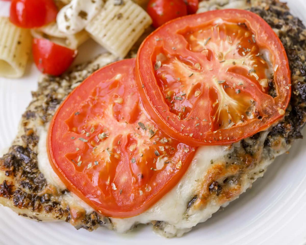 Baked Pesto Chicken topped with mozzarella cheese and two tomato slices.