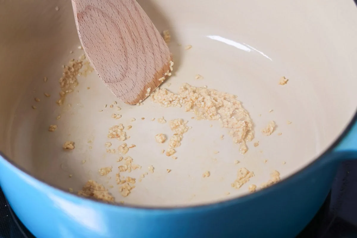 Sauteing minced garlic in a pot.