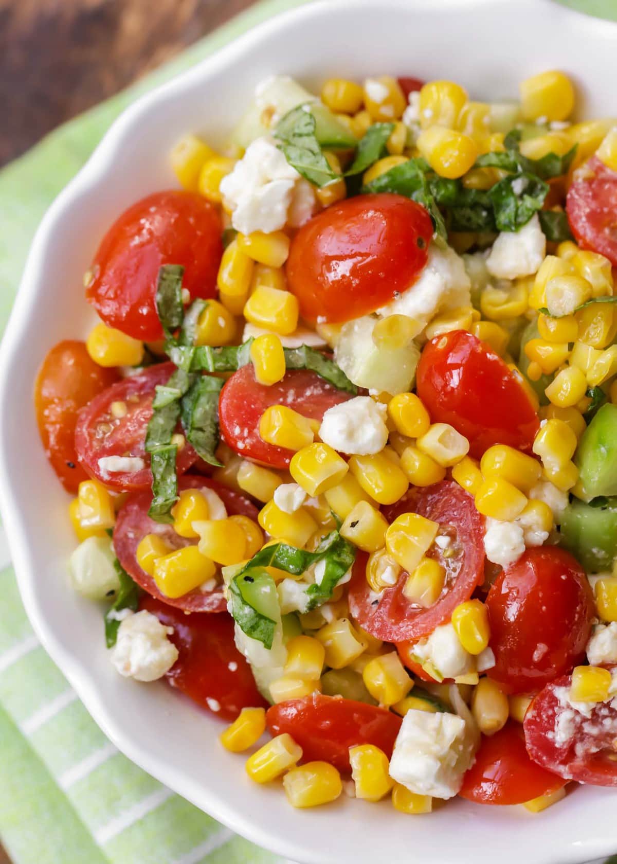 Corn Salad that includes corn, tomatoes, cucumber, cheese, and basil
