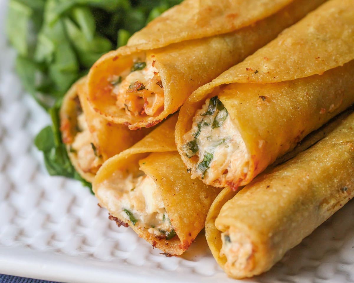 Finger food appetizers - stacked cream cheese and chicken taquitos served on a white plate.