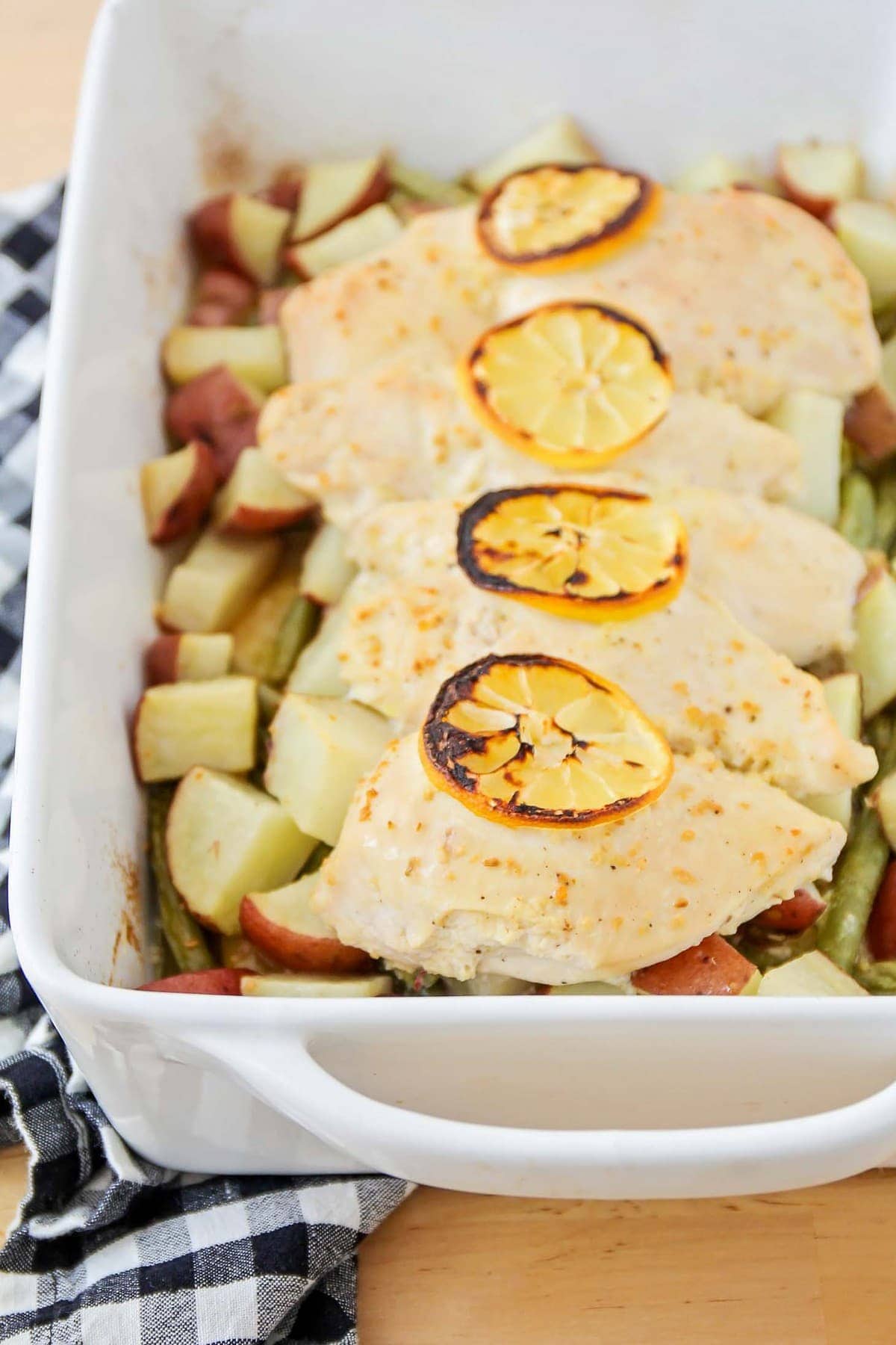 Healthy Dinner Ideas - Lemon Chicken With Vegetables topped with lemon slices in a white baking dish.