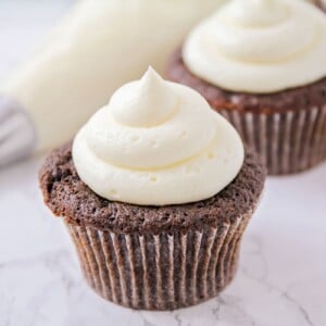 Marshmallow Frosting piped onto two chocolate cupcakes.