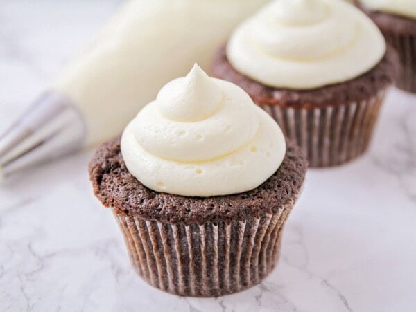 Marshmallow Frosting piped onto two chocolate cupcakes.